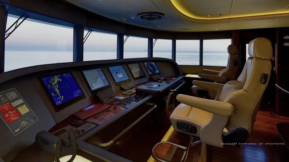 An upholstered helm chair and trimmed dashboard in a wheelhouse at dusk