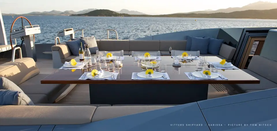 The aft deck of Sarissa set for dinner, upholstered seating against the open sea